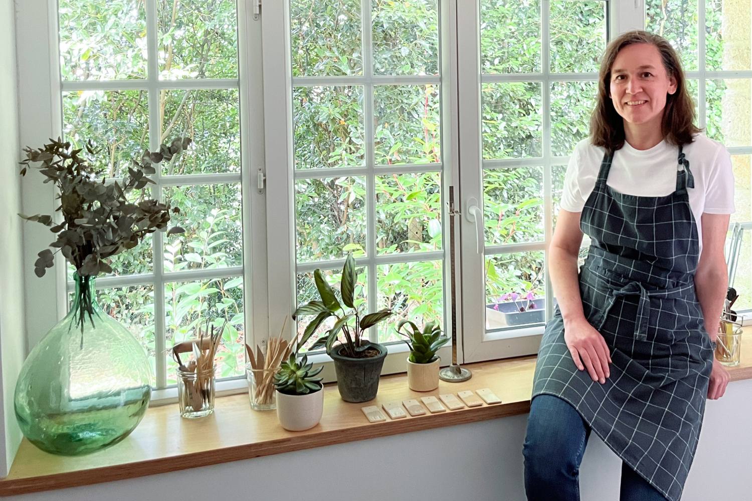 La céramiste Isabelle de l'Atelier les spontanées dans son atelier entourée de plantes vertes