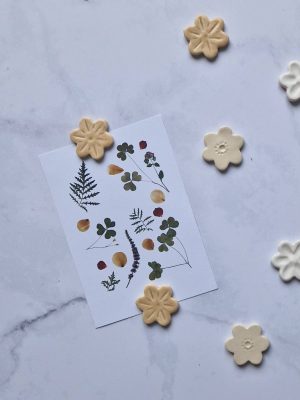 Magnets floraux en céramique de coloris variés posés sur une carte représentant un herbier