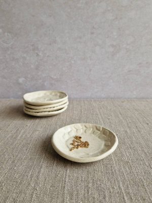 Mini coupelle en grès avec un bijou posée devant une pile de quatre mini coupelles