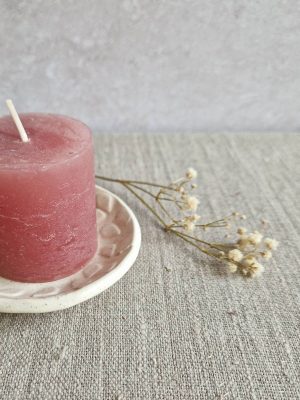 Détail d'un côté de la mini coupelle au motif de feuillage avec une petite bougie rose et un brin de gipsophyle