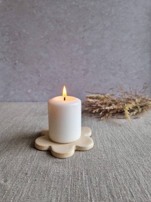 Support Marguerite en céramique avec une bougie blanche allumée et quelques fleurs séchées en arrière-plan