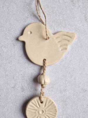 Détail de la suspension murale Céleste avec l'oiseau beige rosé et une perle modelée à la main