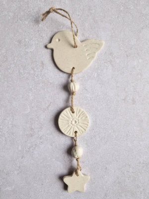 Gros plan sur la suspension murale Céleste avec le motif oiseau en coloris blanc moucheté