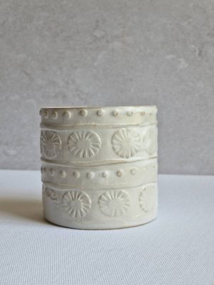 Zoom sur un cache-pot en grès blanc orné de motifs géométriques en relief