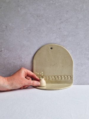 Main posant un vase miniature sur une étagère en céramique de l'Atelier les spontanées