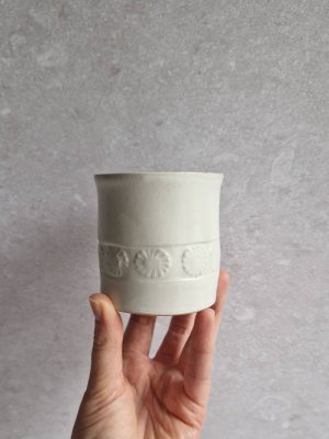 Une main présentant une tasse Pâquerettes en grès émaillé blanc