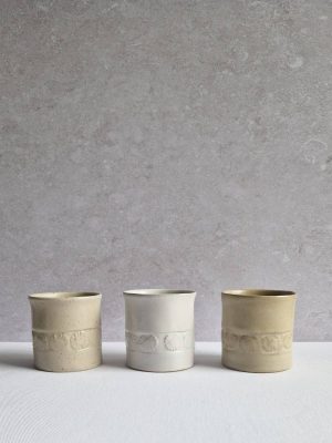 Trois modèles de tasse à café Pâquerettes de l'Atelier les spontanées émaillées en blanc, beige et beige pyrité